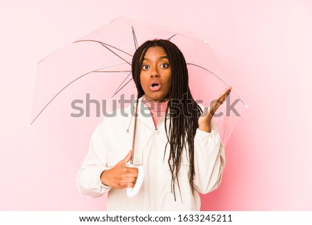 Young african american woman holding an umbrella isolated surprised and shocked.