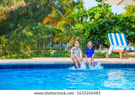Family enjoying summer vacation in luxury swimming pool. Father and daughter splashing and having fun