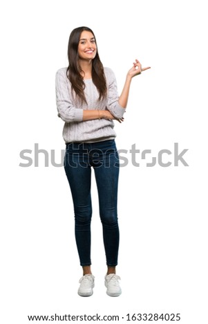 A full-length shot of a Young hispanic brunette woman pointing finger to the side over isolated white background