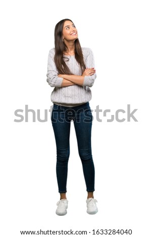 A full-length shot of a Young hispanic brunette woman looking up while smiling over isolated white background