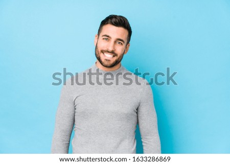 Young caucasian man against a blue background isolated happy, smiling and cheerful.