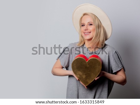Beautiful blonde woman with heart shape box on white background 