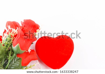 Flat lay view of artificial red roses with heart shape and wooden frame on white background. Love and Valentine's Day concept. Selective focus.