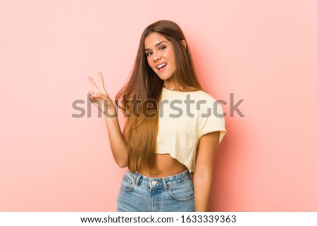 Young slim woman joyful and carefree showing a peace symbol with fingers.