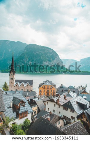 hallstatt church with bell tower lake with alpine mountains on background