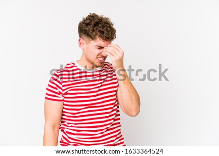 Young blond curly hair caucasian man isolated having a head ache, touching front of the face.