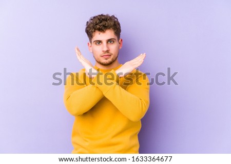 Young blond curly hair caucasian man isolated keeping two arms crossed, denial concept.