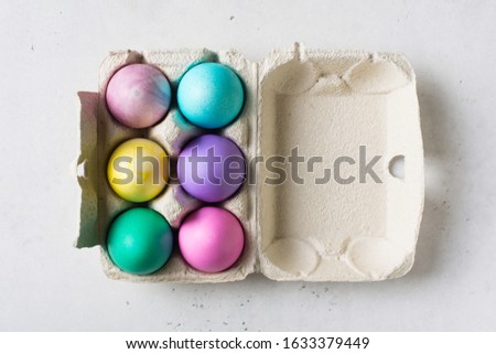 Colorful eggs in carton. Easter and spring theme on white background, copy space, top view
