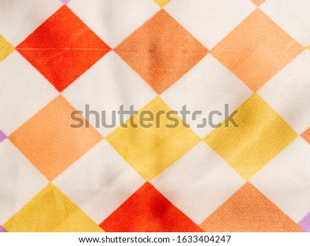 Fragment of white silk fabric with geometric pattern in form of multicolored squares arranged in staggered order