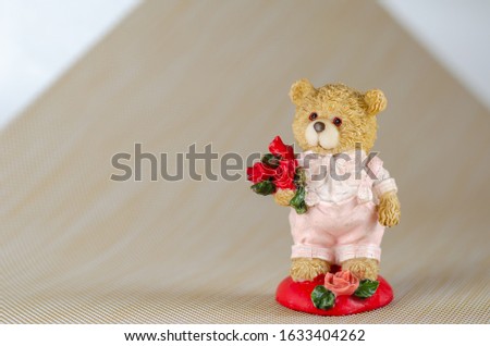 Figurine of a bear in love with a bouquet of flowers.A little cute teddy bear holds in his paw a bouquet of flowers for his beloved. Free space for text on the left. Eye level shooting. 