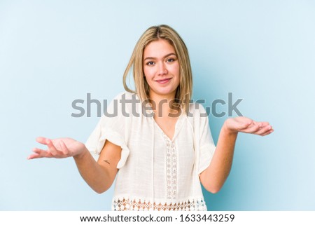 Young blonde caucasian woman isolated doubting and shrugging shoulders in questioning gesture.