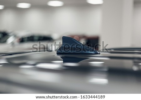Close-up GPS antenna shark fin shape on a roof of car for radio navigation system. Antenna shark fin on blurry background. Car detail. Classic blue color