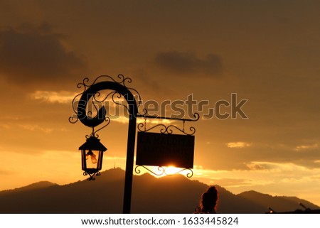 Photograph of a vintage lamp and sign at sunset