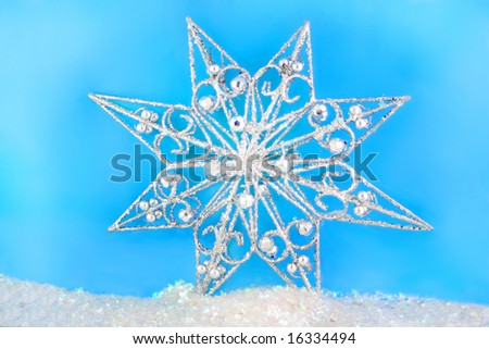  sparkly christmas star on blue background and glitter snow