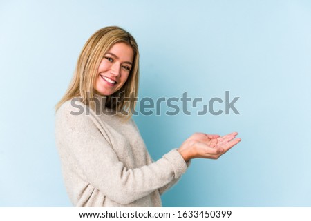 Young blonde caucasian woman isolated holding a copy space on a palm.