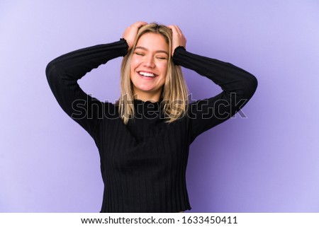 Young blonde caucasian woman isolated laughs joyfully keeping hands on head. Happiness concept.