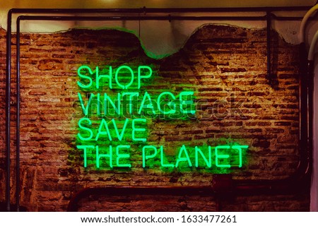 Neon sign. Shop vintage, save the planet. Beautiful green neon against a red brick wall. Taken at vintage shop in Barcelona.