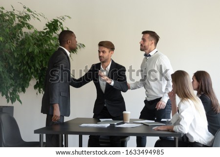 During group meeting African and Caucasian business partners having conflict fighting, colleague stop a scuffle, multiracial people express aggression negative attitude, racial discrimination concept Royalty-Free Stock Photo #1633494985