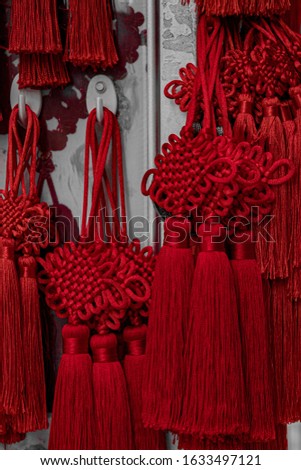Closeup of braid texture of traditional red Chinese decorations with woven patterns and long tassels. Texture of yarn souvenirs for Lunar New Year celebration.