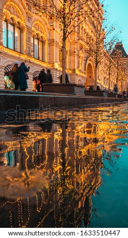 Moscow State Department store in the reflection in a pool of water.People walk with children,on red square Near the Kremlin.People in warm clothes.Vertical. .Template,design.Christmas lights.