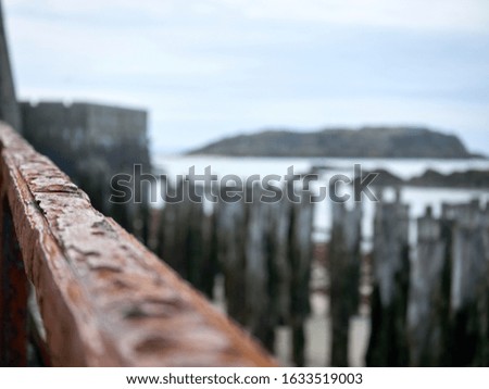 Rusty steel railings near the sea, with the beach in the background. Photo taken in Saint-Malo, France.