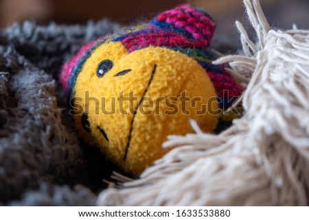 Colourful toy monkey with yellow face smiling. Monkey cosy in blankets ready to go to sleep. Monkey looks happy and peaceful in a comfortable home. Ready for bed. Going to sleep.