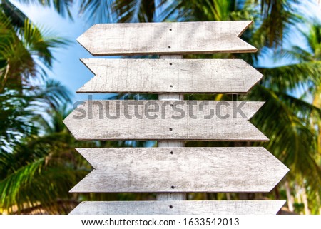 Wooden signpost on a background of palm trees on a tropical island