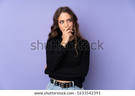 Young woman over isolated purple background having doubts and with confuse face expression