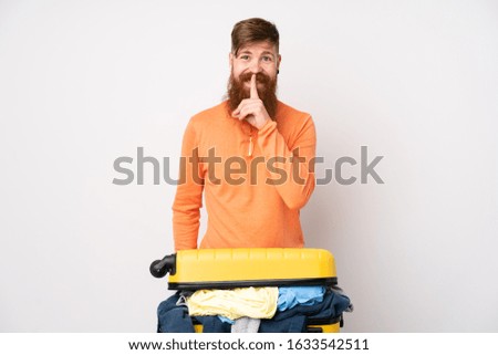 Traveler man with a suitcase full of clothes over isolated white background doing silence gesture