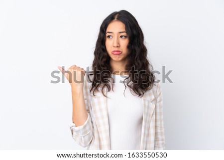 Mixed race woman over isolated white background unhappy and pointing to the side