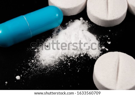 White medical pills and tablets on black background. Closeup photo of medical preparations with copy space