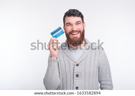 You should get one of this cool credit cards. Excited bearded man is holding a credit card on white background.