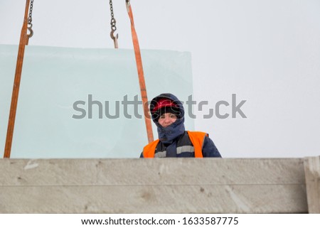 Worker slinger in orange reflective vest and helmet unloads ice panels