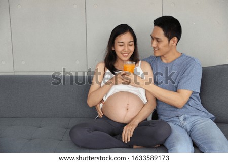 young asian healthy pregnant woman and husband  smile while holding a glass of orange juice (health care concept)