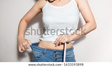 Young slim woman in oversized blue jeans. Fit woman wearing too large pants. Healthcare and woman diet lifestyle concept to reduce belly and shape up healthy stomach muscle. Royalty-Free Stock Photo #1633593898