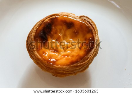 Portuguese pasteis of cake with custard on white plate on textured background.