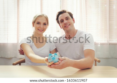 money, home, finance and relationships concept - smiling couple with piggybank 
