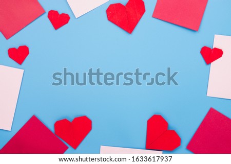 The red paper heart shapes and envelope over the blue background. Greeting cards, Love and Valentines day concept. Flat lay, top view, copy space.
