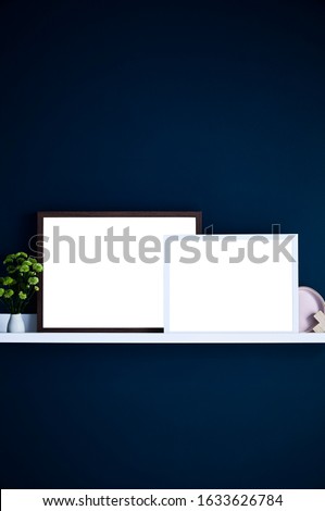 Photography of a shelf with decorator items and empty frames against a dark blue wall