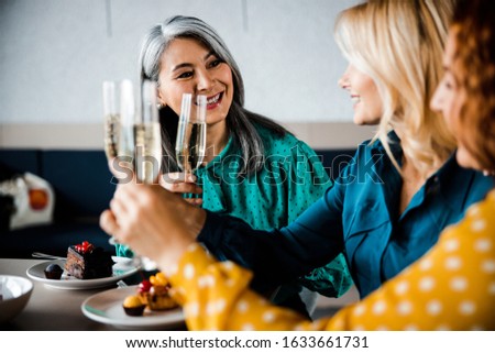 Beautiful happy ladies clinking glasses of champagne stock photo