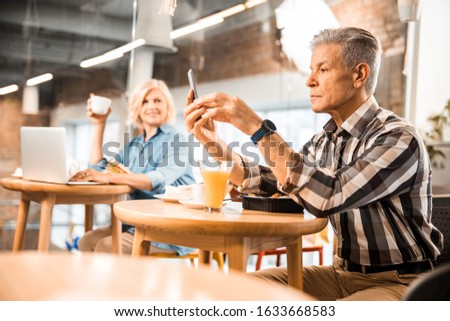Mature male with smart watch having lunch with woman in the background stock photo