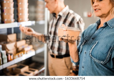 Cropped photo of smiling lady standing and holding food box in shop stock photo