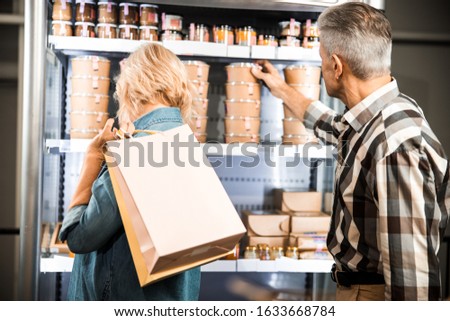 Back view of man and woman standing in supermarket with shopping packages stock photo