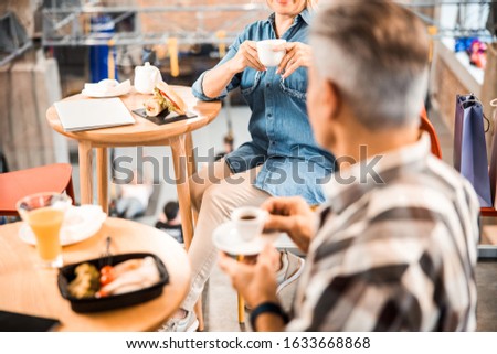 Cropped photo of mature woman and man talking while sitting in cafe stock photo