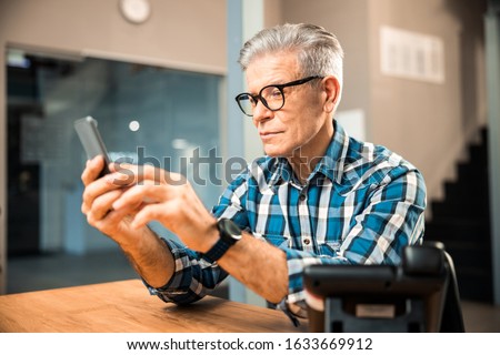 Waist up of smiling male wearing smart watch and using mobile phone stock photo