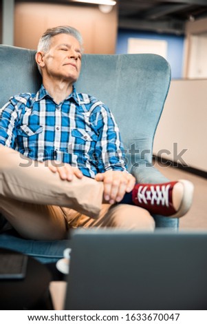Mature male with eyes closed resting in cafe stock photo