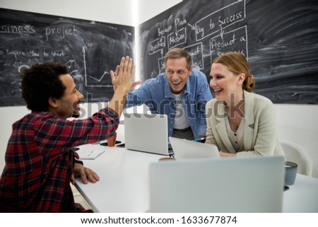 Cheerful men giving high five while pretty lady looking at them and smiling stock photo