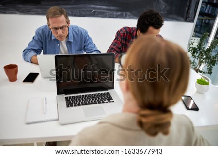 Two men and woman working on notebooks stock photo. Teamwork and modern technology concept