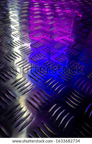 Reflection of colored display cases in a metal shiny floor.