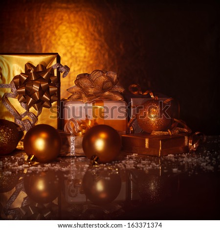 Picture of golden gift boxes on dark grunge background, variety of presents decorated with Christmas tree toys, studio shot, happy New Year greeting card